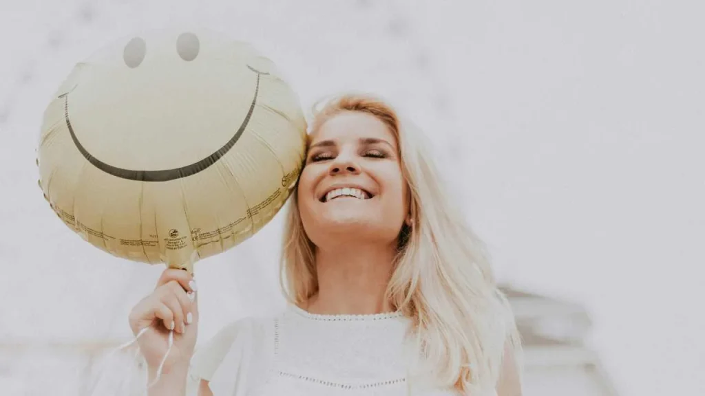 Lady smiling and holding a happy face ballon