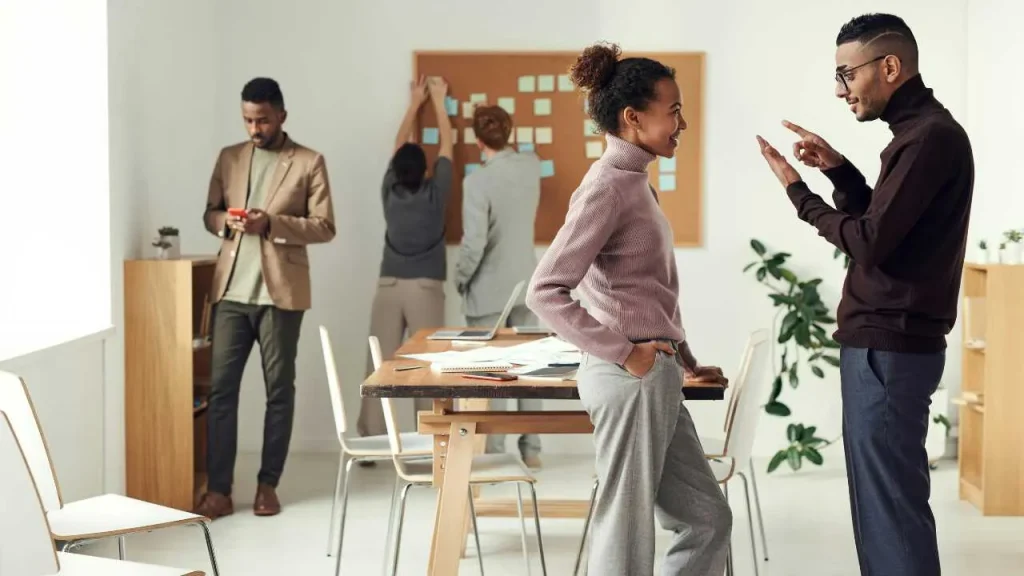 A lady and a guy discussing in an office standing.