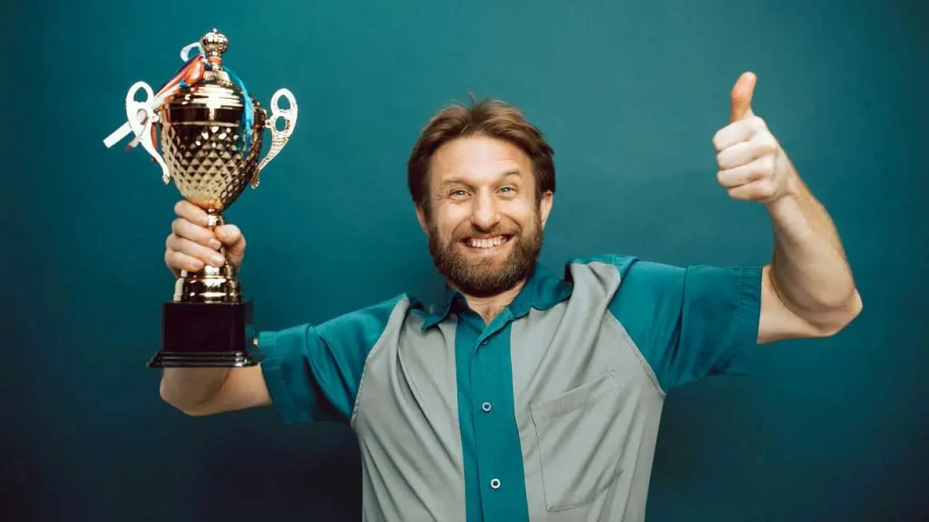 A man happily holding a trophy as a way of improving productivity in the workplace