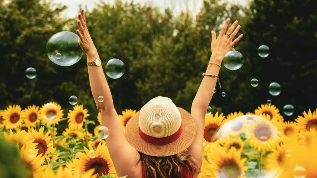 A lady raising up her hands surrounded by flowers