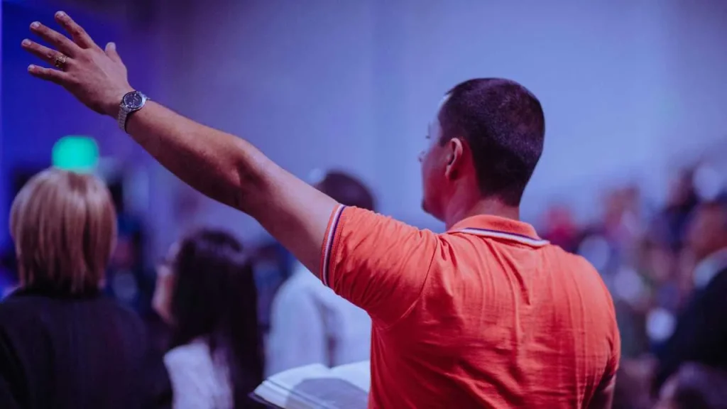 A man holding a Bible in his right hand and lifting his left hand in worship