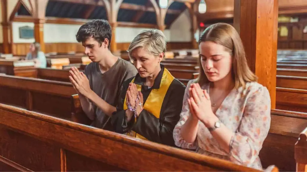 Two females and a male kneeling in a church and praying representing how to stop worrying and start living