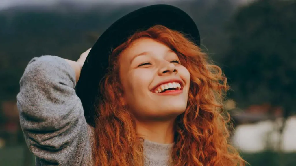 A joyful lady with red hair and black hat