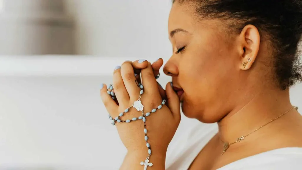 A woman praying with her eyes closed representing how to stay persistent