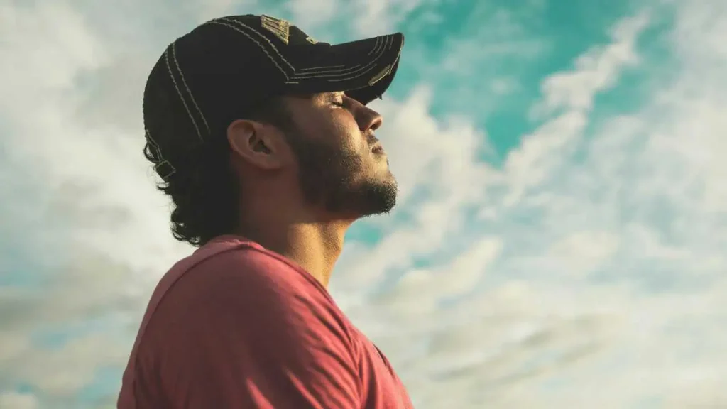 A man on red shirt looking into the sky with his eyes closed representing how to forgive