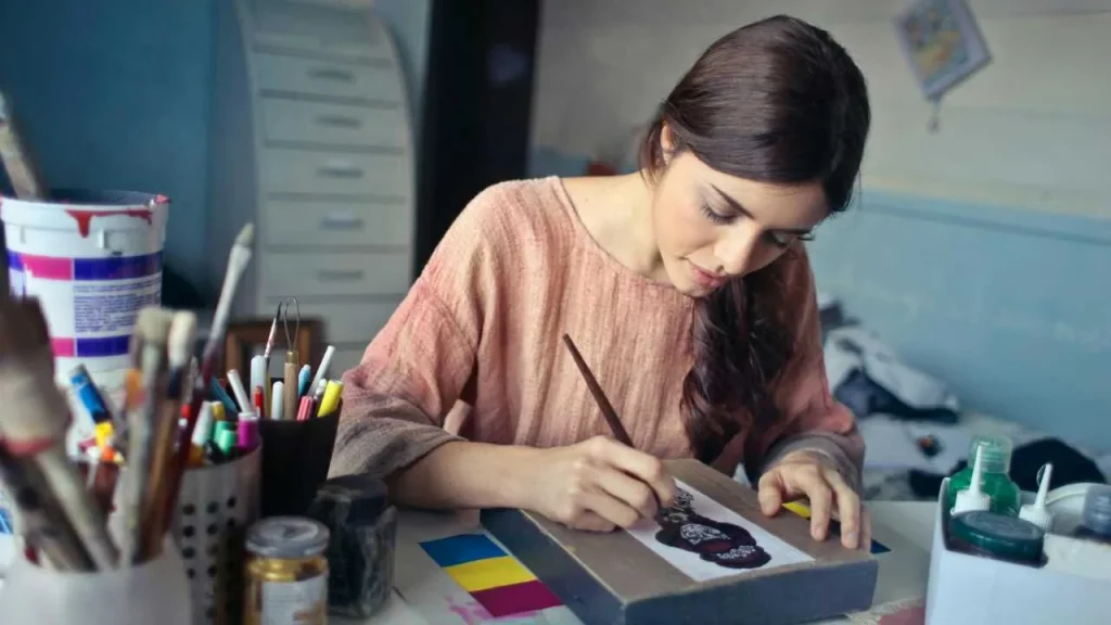 A lady painting on a book placed on a desk