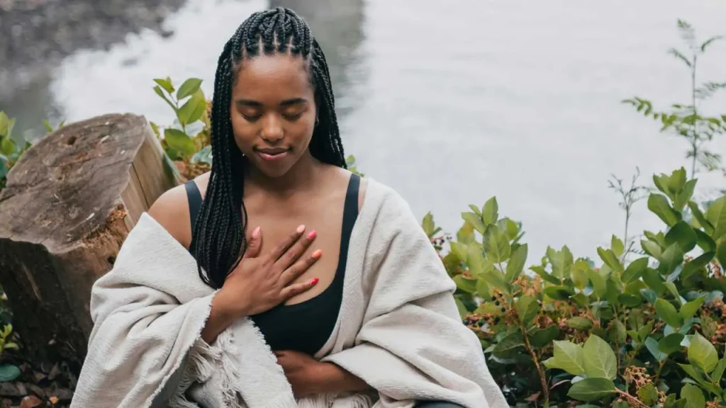 A dark skin lady, mediating in an open space.