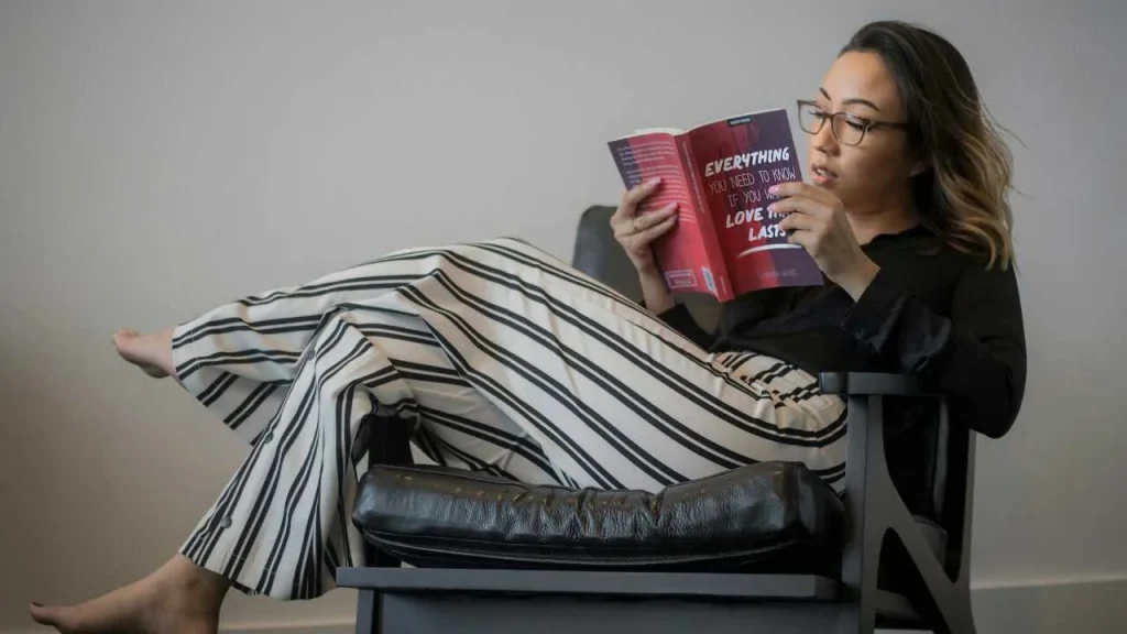 A lady on a couch reading a book about self love.