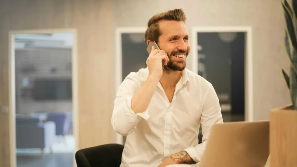 A man in white sleeves happily making a phone call