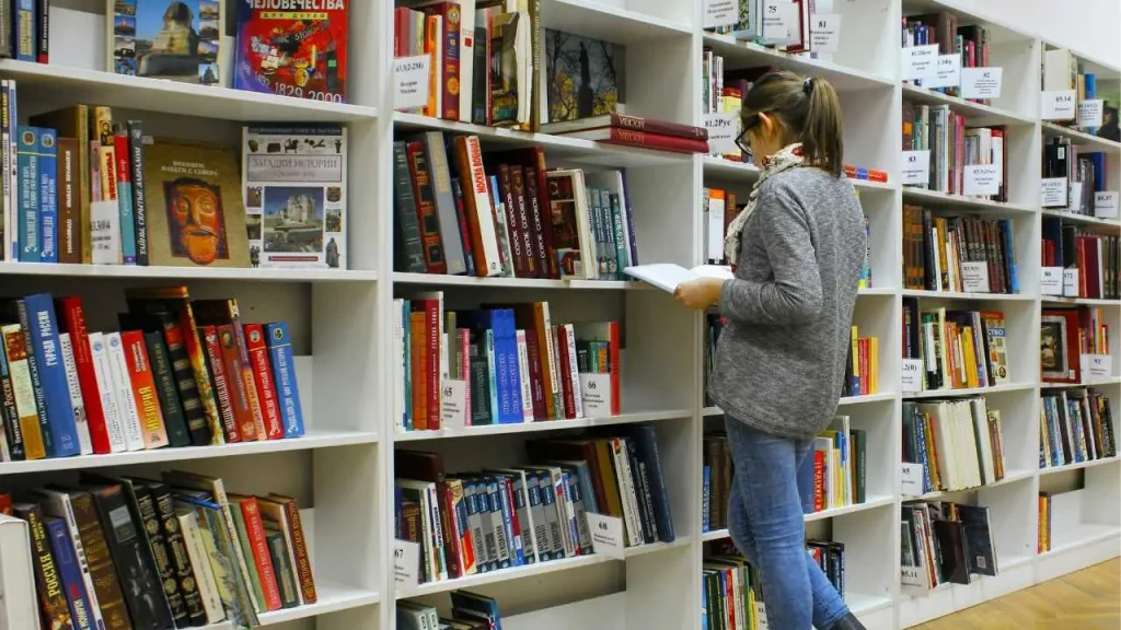 A lady searching for books from a book shelf 