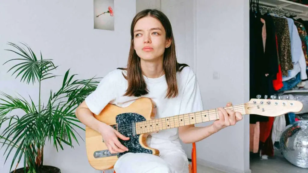 A lady in white outfit playing a guitar—representing how to turn your passion into a career