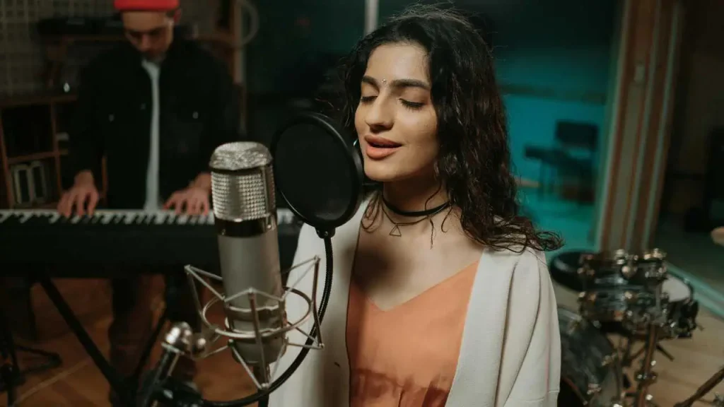 A lady passionately singing to a hunged mic in a studio