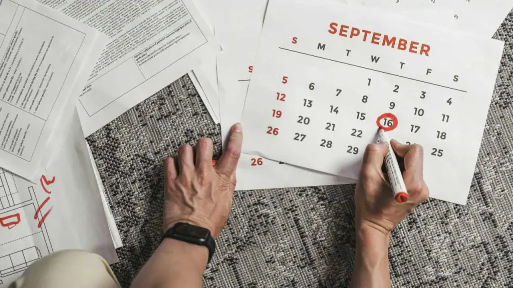 A hand circling a date on a calendar with red ink