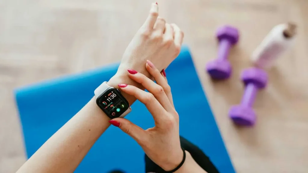 A lady checking her wrist watch with gym equipment on the floor