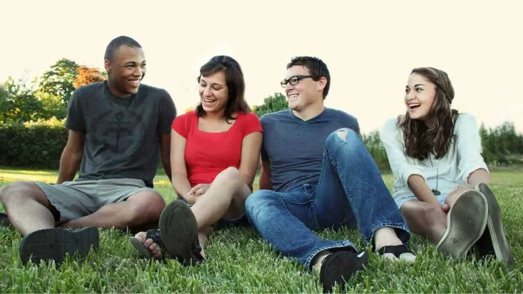 A group of friends discussing happily on the grass