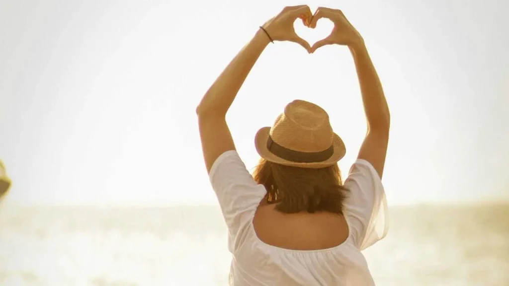 A lady raising her hands up in a love shape 