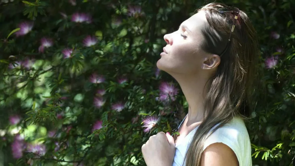 A lady looking up with her eyes closed and her hands on her chest