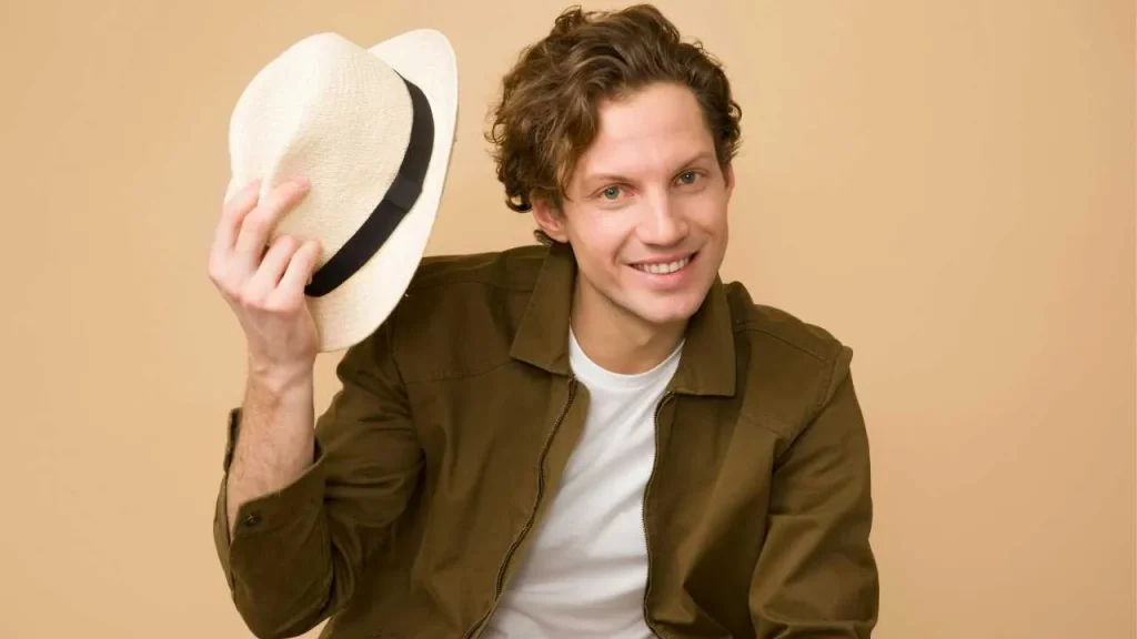 A guy on brown coat raising his hat on one hand
