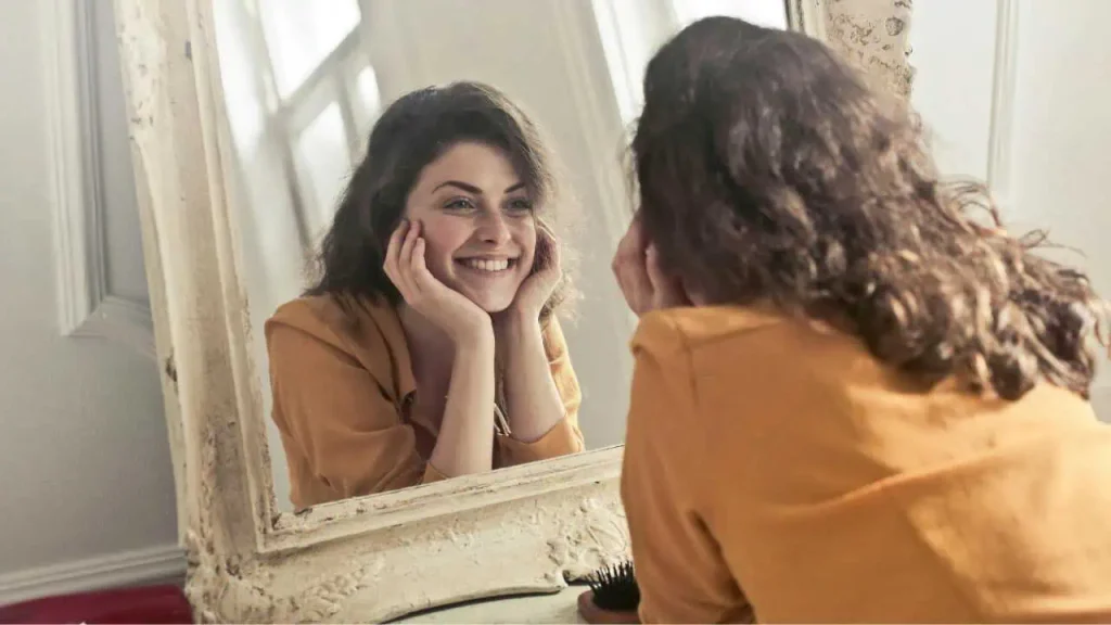 A lady smiling and looking into the mirror