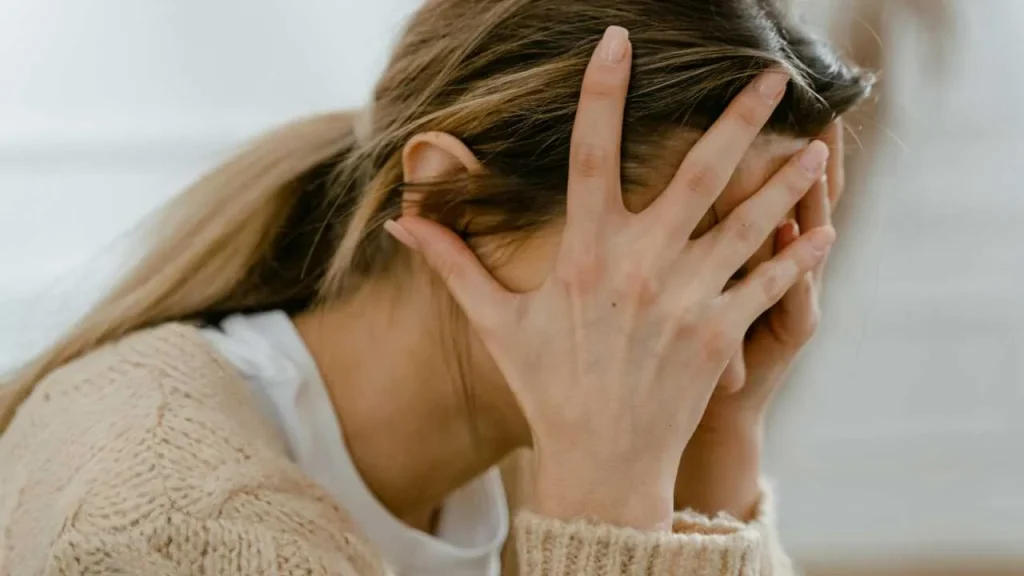 A lady covering her face with her hands representing what does insecure feelings means.