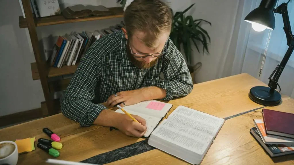 A man studying his bible and taking notes depicting i am the light of the world