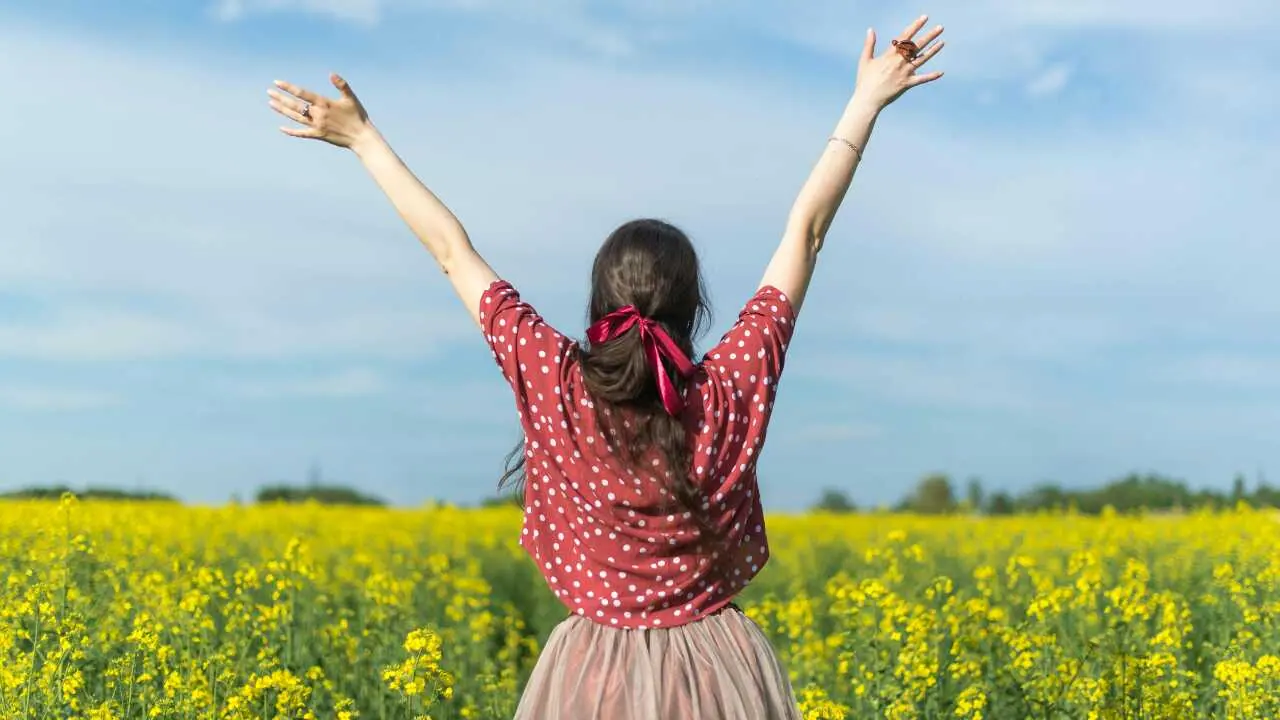 A lady lifting both hands in the air depicting have faith in God for He cares for you