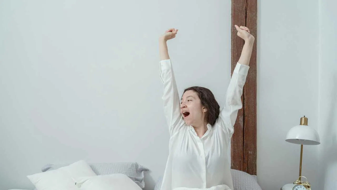 A lady stretching on her bed depicting how waking up early can change your life