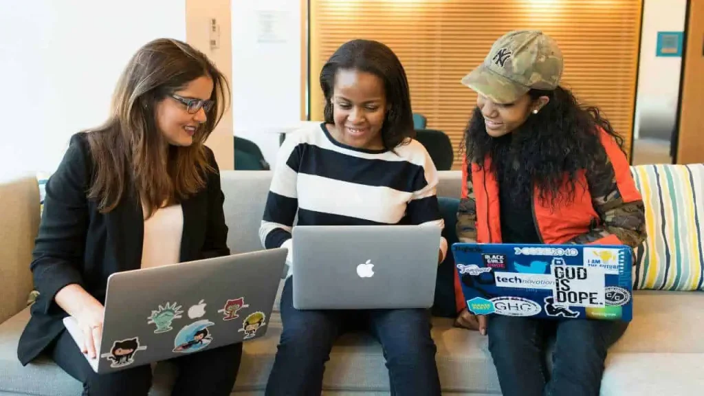 Three ladies typing on a laptop