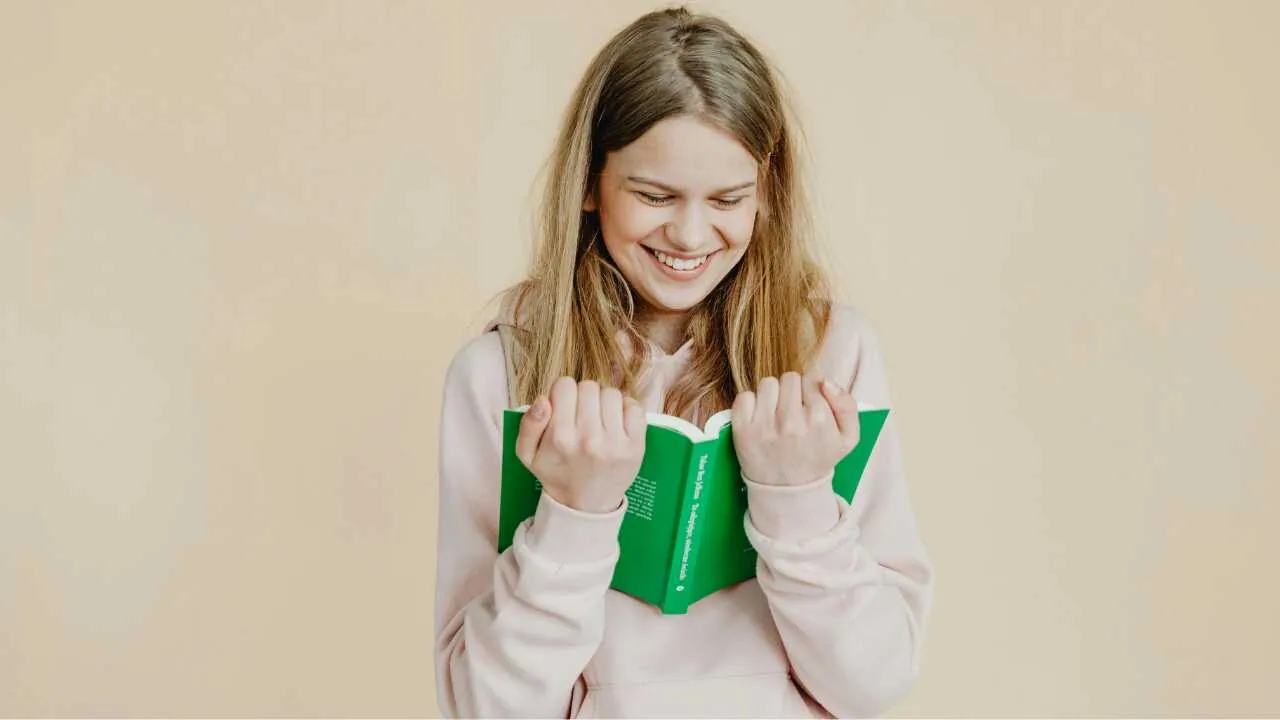 Ways to build growth Mindset Joyful lady holding a green book depicting ways to build growth mindset