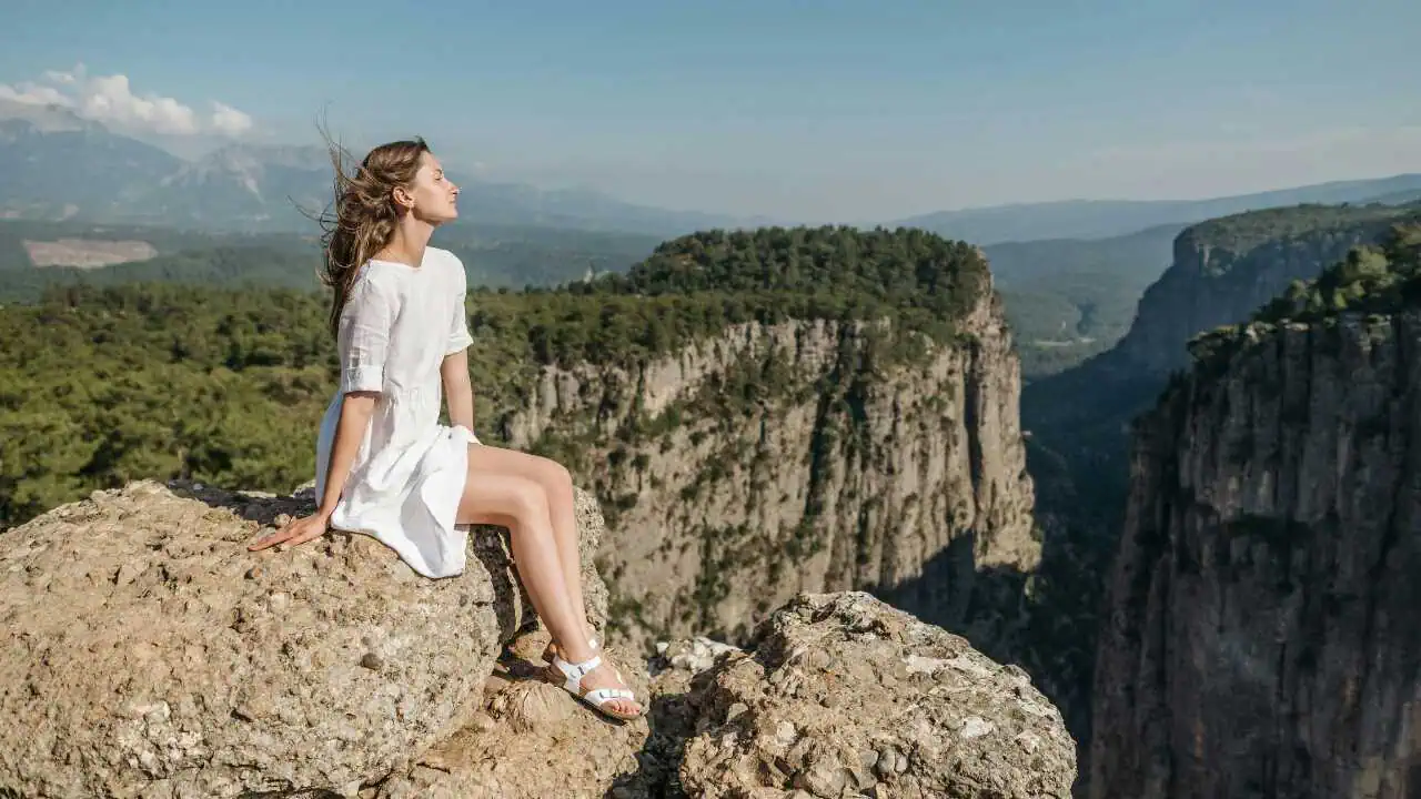 Quotes on Strength A lady in white sitting on a hill edge depicting quotes on strength