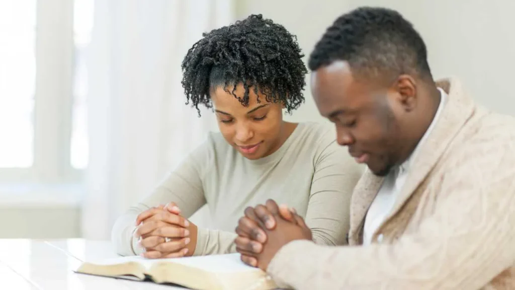 A man and a woman praying depicting you're more than a conqueror through prayers