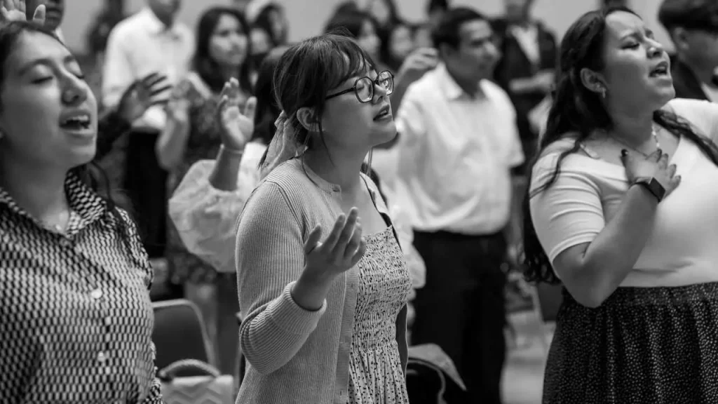 A group of persons in worship depicting you're more than a conqueror through praise