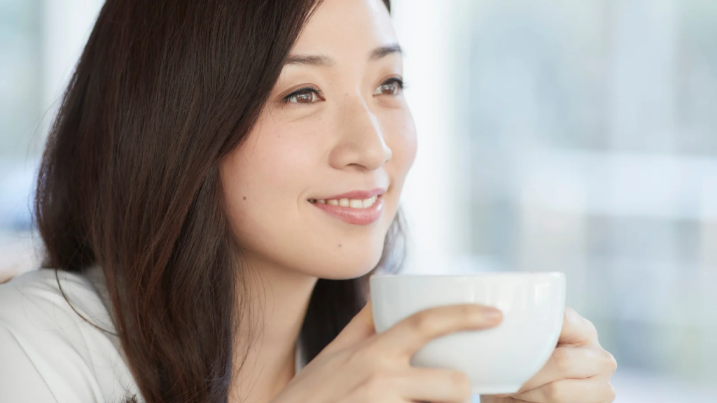 A lady looking away with a cup of coffee in her hands