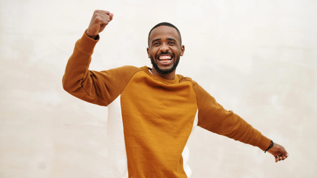 An excited young man on a brown sleeve raising one one up