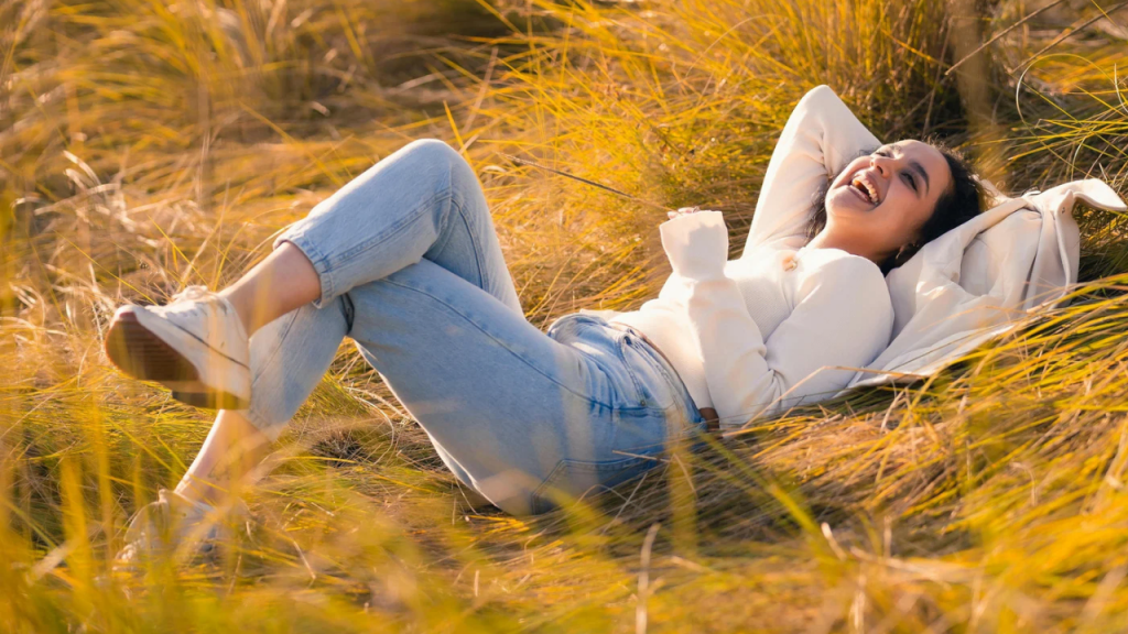 A happy lady laying on an open grass depicting how to know God is right beside you