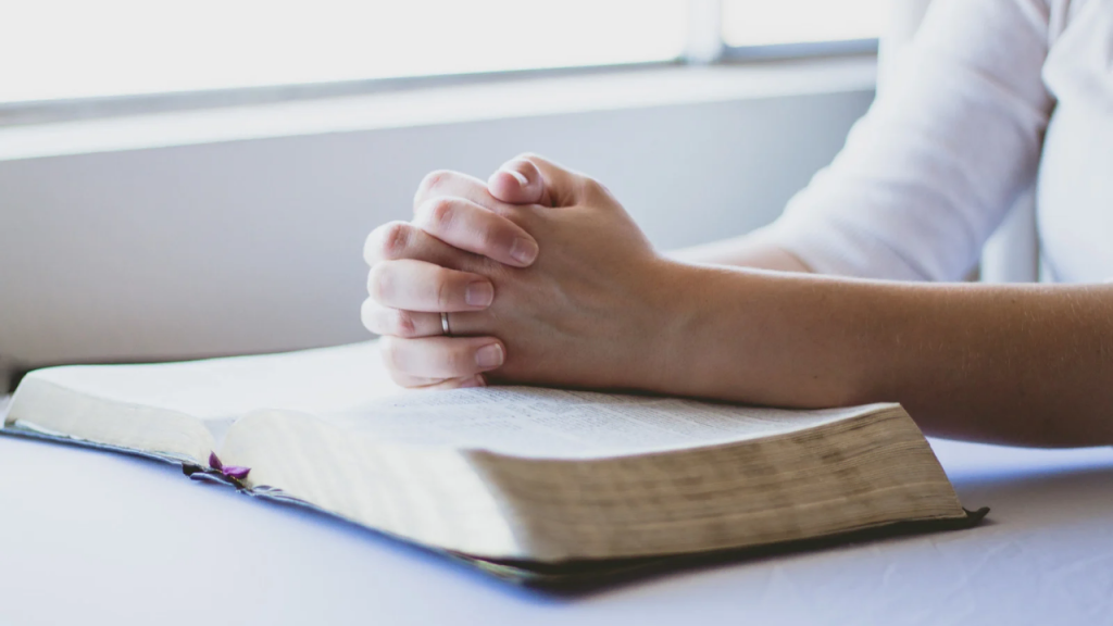 A hand placed on an opened Bible depicting a guide to spiritual growth and inner peace