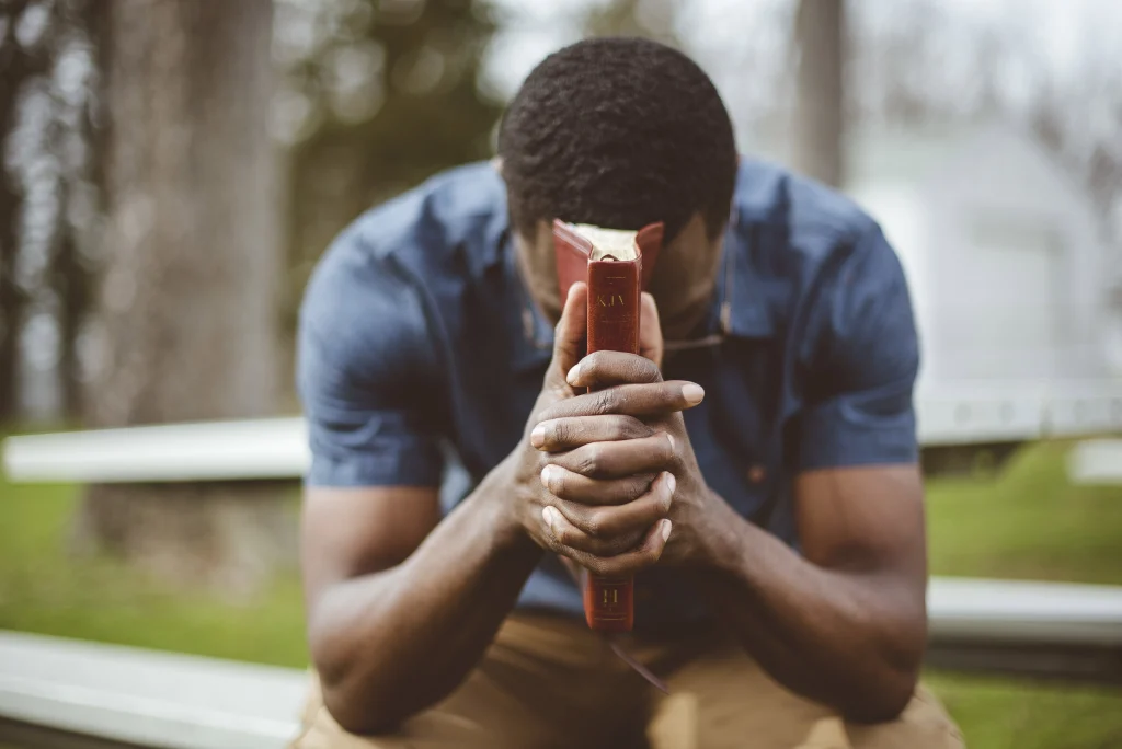 A man holding a Bible in a praying position depicting how to trust God for the impossible 