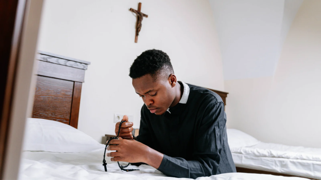 A young man in black kneeling to pray depicting a guide to spiritual growth and inner peace