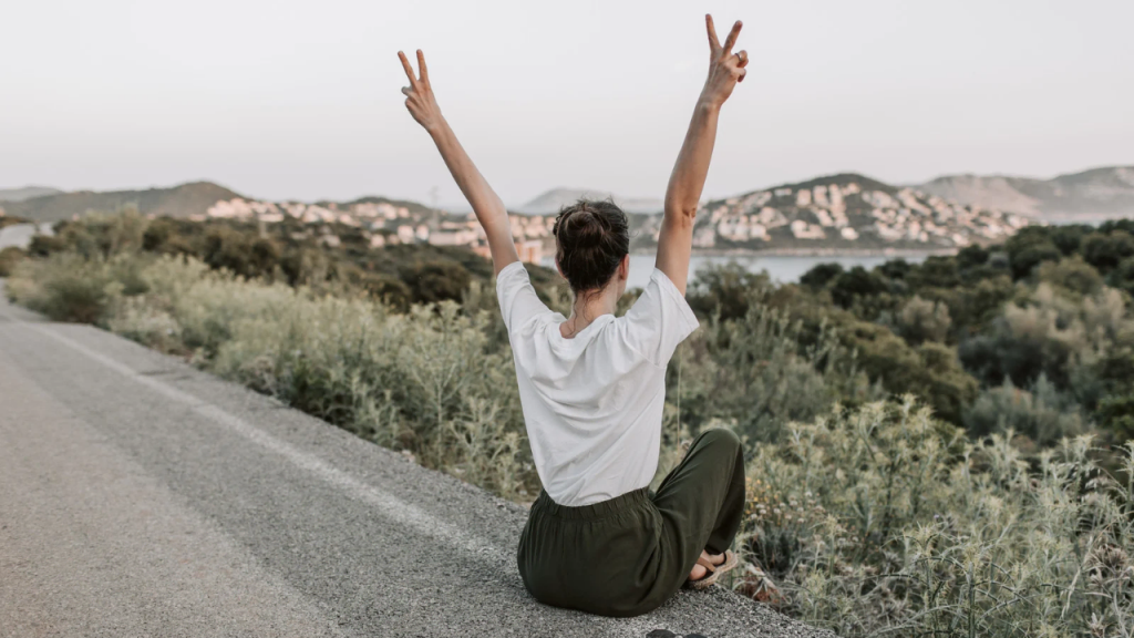 A lady throwing her hands up in the air depicting peace