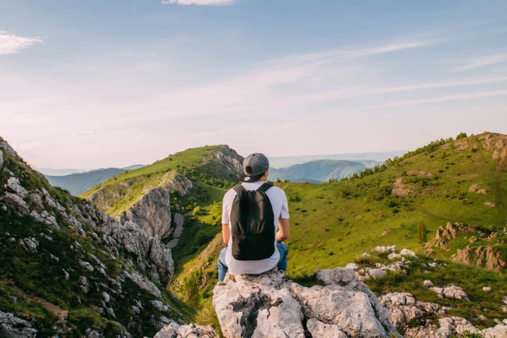A young man facing backwards on a hill top
